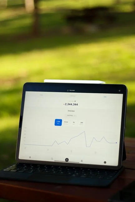 Hands typing on a laptop with cryptocurrency charts and smartphone display in view, focusing on digital finance.